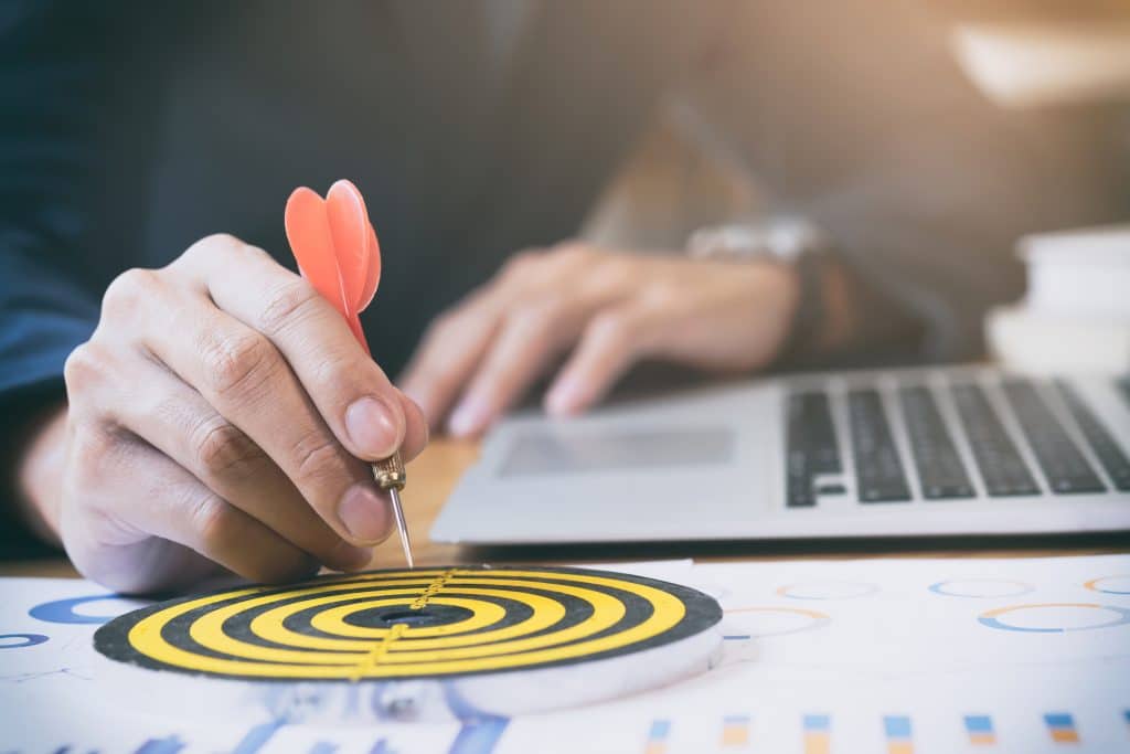 a hand holding a dart, pointing a yellow board for business strategy